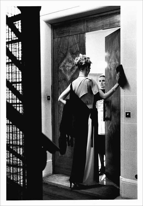 Zwei Frauen im eleganten Abendkleid beim Türöffnen, eine schaut in den Spiegel.