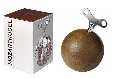 Box mit "Mozartkugel" und Holz-Kugel mit Metall-Teil oben.