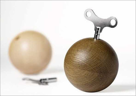 Holzball mit Metallspindel und Metallring, daneben ein weiterer Holzball und ein Metallwerkzeug.