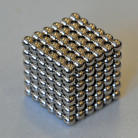 Ein Würfel aus kleinen, glänzenden Metallkugeln.