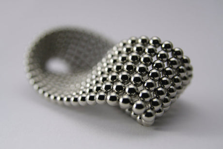 Eine flexible Kugelkette aus kleinen, glänzenden Metallkugeln.