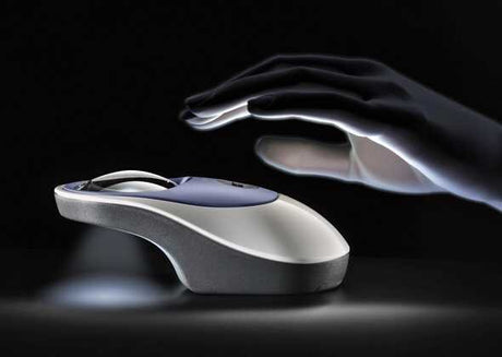Hand über Computermaus in dunklem Hintergrund, Lichtreflexe auf der Maus.