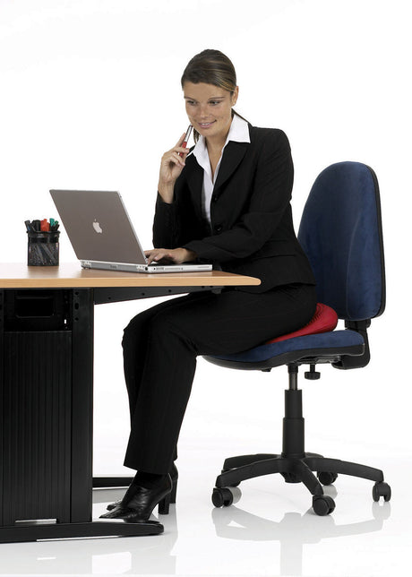 Frau in Businesskleidung sitzt auf einem Bürostuhl, arbeitet an einem Laptop und telefoniert.