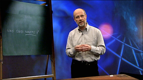 Mann steht vor einem schwarzen Brett mit der Aufschrift "Was sind WARP's?" und einem digitalen Hintergrund.