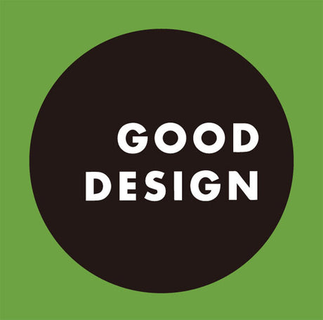 Schwarzer Kreis mit weißen Text "GOOD DESIGN" auf grünem Hintergrund.