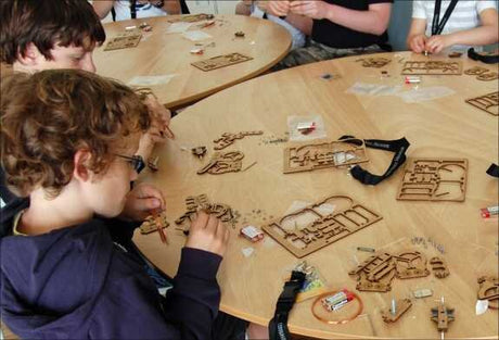 Mehrere Kinder sitzen um einen runden Tisch und bauen mit Holz-Puzzles und kleinen Bauteilen.