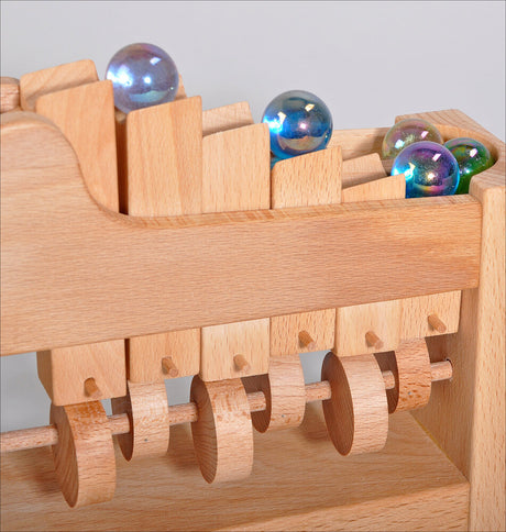 Holzspielzeug mit bunten Glaskugeln auf einer Holzbahn.