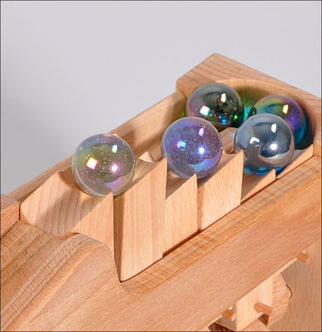 Mehrere bunte Glaskugeln in einem Holzspielzeug mit Schienen.