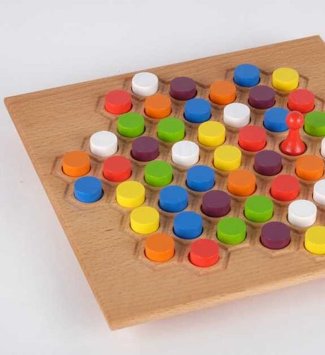 Brettspiel mit bunten, runden Spielsteinen und einer roten Spielfigur auf Holzbrett.