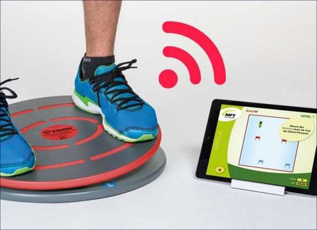 Ein Fuß steht auf einem roten, runden Balance-Board, daneben ein Tablet mit einer digitalen Spielanzeige und ein rotes WLAN-Symbol