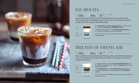 Ein Glas Eiskaffee mit Milch, Eiswürfeln und Schokoladensirup, daneben bunte Strohhalme auf einem grauen Untergrund.