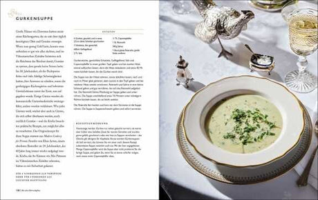 Gurkensuppe in einer weißen Schale mit goldener Umrandung, daneben Salz, Pfeffer, Knoblauch, Wein und Salzstreuer