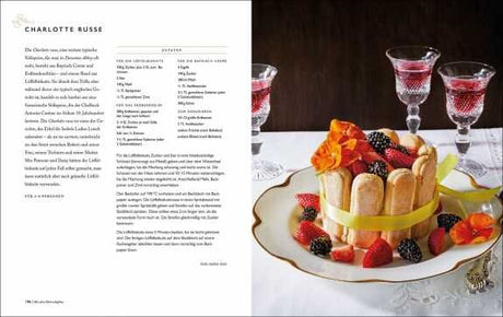 Buchseite mit Text auf der linken Seite und auf der rechten Seite ein Kuchen mit Biskuitrollen, Beeren, Fruchtgummi und Dekoration