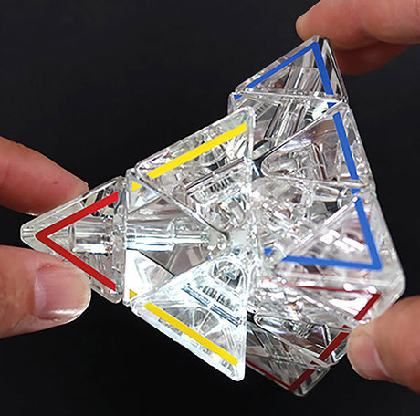 Hand hält einen transparenten, geometrischen Kristallwürfel mit farbigen Linien (rot, blau, gelb).