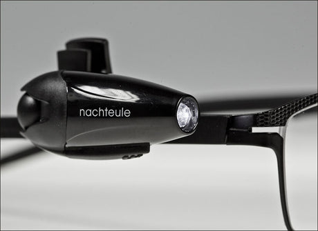 Schwarze Stirnlampe mit dem Schriftzug "nachtule" und einem LED-Licht, auf einer weißen Oberfläche.
