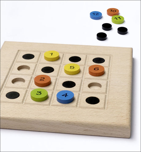 Holzspiel mit bunten, nummerierten Ringen und schwarzen, leeren Feldern auf weißem Hintergrund.
