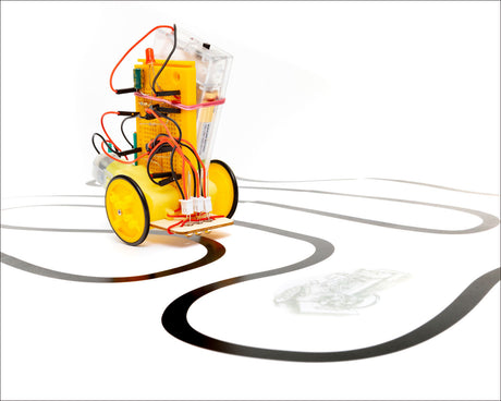 Kleiner Roboter mit gelben Rädern, elektronischen Komponenten und Kabeln auf einer weißen Oberfläche mit schwarzen Linien.