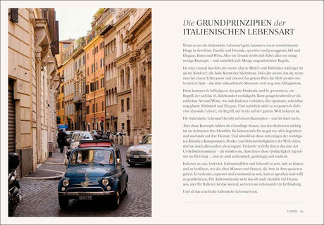 Blick auf eine enge, gepflasterte italienische Straße mit alten Gebäuden und einem blauen Fiat 500.