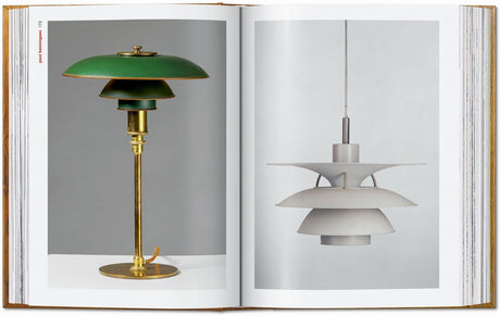 Zwei Designer-Lampen, eine grüne mit goldfarbenem Standfuß, die andere weiße mit mehreren Schichten, hängen an einer Buchseite.