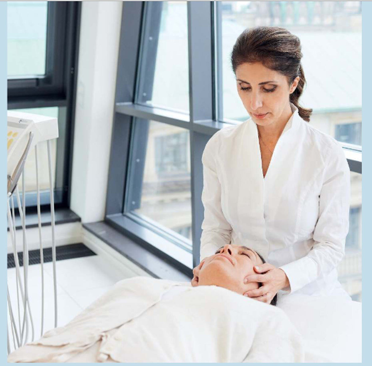 Ärztin führt eine Gesichtsmassage bei Patientin im Krankenhaus durch.