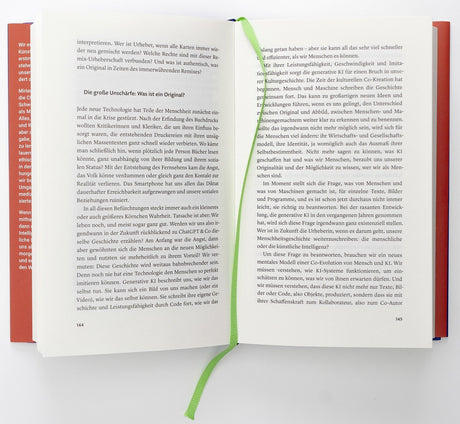 Offen gebundene Buch mit grünem Lesezeichen, sichtbarer Text auf beiden Seiten.
