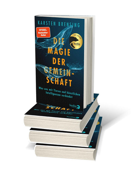 Buchcover mit blauen Walen, Titel "Die Magie der Gemeinschaft", Autor Karsten Brensing, und einem goldenen Siegel.