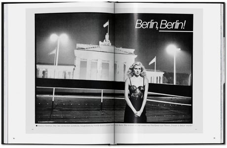 Schwarz-Weiß-Foto einer Frau in einem eleganten Kleid vor dem Brandenburger Tor in Berlin, nachts, mit Straßenlaternen.