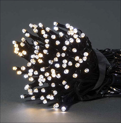 Lichterkette mit vielen kleinen, leuchtenden LEDs, aufgerollt und auf dunklem Hintergrund.