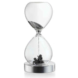 Ein Sanduhr mit schwarzem Sand, der im oberen Teil beginnt zu fließen, und einer kleinen Pflanze am unteren Ende.