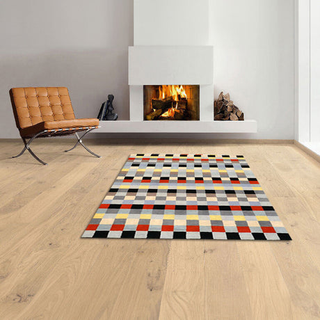 Wohnzimmer mit Kamin, braunem Sessel, Holzfußboden und buntem geometrischem Teppich.