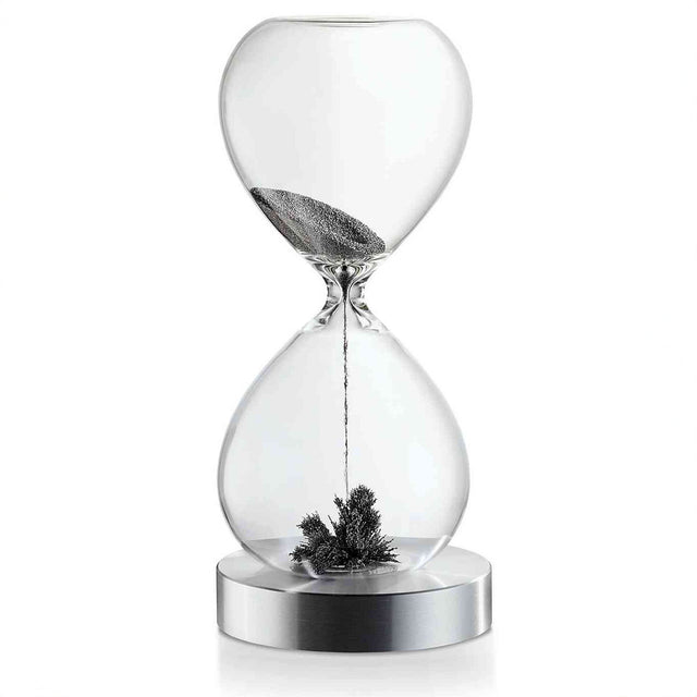 Ein Sanduhr mit schwarzem Sand, der im oberen Teil läuft und im unteren Teil eine kleine Pflanze oder Zweig liegt.