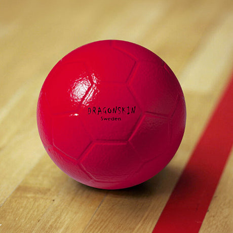 Roter Ball mit "DRAGONSKIN Sweden" Schriftzug, auf Holzboden mit roter Linie.