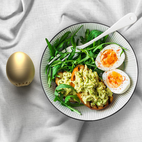 Bunter Teller mit Avocado-Toast, Salat, daneben ein goldenes Piepei.