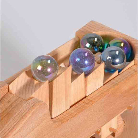 Holzspielzeug mit bunten Glaskugeln in einer Vertiefung.