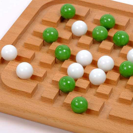 Holzbrett mit grünen und weißen Kugeln, die in Vertiefungen liegen, für das Brettspiel Mühle.