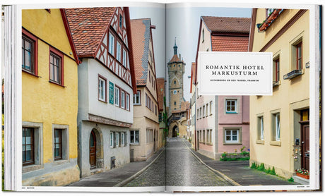 Bunte Häuser an einer engen, gepflasterten Straße mit einem Turm im Hintergrund.