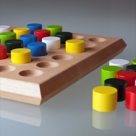 Holzspielbrett mit farbigen, runden Spielsteinen, einige liegen daneben.