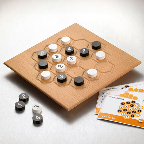 Holzbrettspiel mit schwarzen, weißen und grauen Spielsteinen, Spielanleitung liegt daneben.